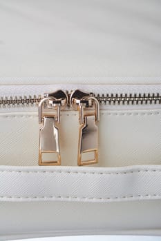 gold zippers with gold zippers are fastened on a white leather object, close-up. High quality photo