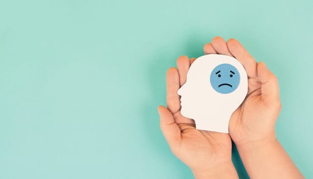 Holding a head with a sad face in the hands, mental health concept, negative mindset, depression, support and evaluation symbol
