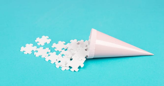 Cone with white puzzle pieces, blue background, spreading the jigsaw parts, searching for ideas and solutions, brainstorming as a team, flat lay