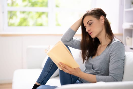 Adult Person Sitting On Sofa Reading Book. Relaxation Lifestyle