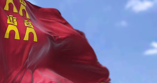 The Region of Murcia flag waving in the wind on a clear day. Region of Murcia is an autonomous community of Spain located in the southeast part of the Iberian Peninsula