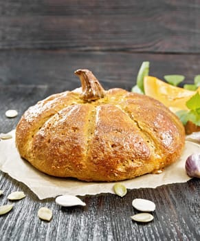 Pumpkin bread on paper, garlic, basil, pieces and seeds of a vegetable on a wooden board background
