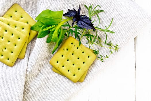 Dry biscuits with spinach, purple basil. rosemary and thyme on a towel on a light wooden board background from above