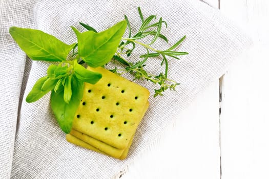 Dry cookies with spinach, rosemary and thyme on a napkin on background of wooden board from above