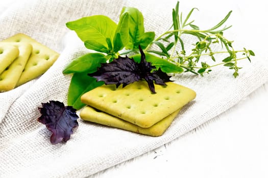 Dry biscuits with spinach, purple basil. rosemary and thyme on a towel on a light wooden board background
