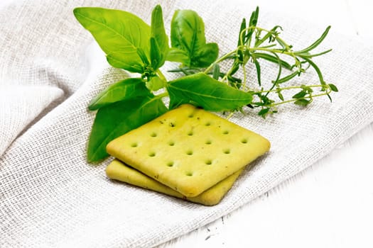 Dry cookies with spinach, rosemary and thyme on a towel against a wooden board background