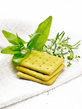 Dry cookies with spinach, rosemary and thyme on a napkin against a wooden board background