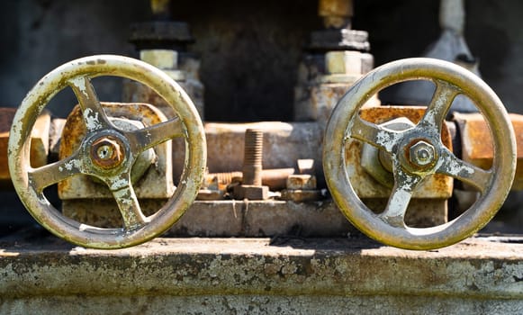 front view closeup of two aged grunge rusted industrial valve wheels
