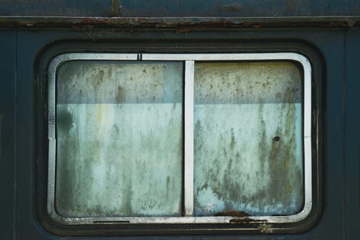 front view closeup of old rusted car window with metallic chrome frame and dirty opaque glass rectangular shape