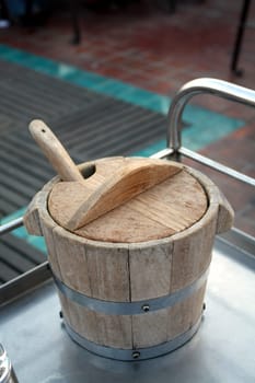 Old wooden bucket for ice on the stainless steel table in the restaurant. Selective focus.