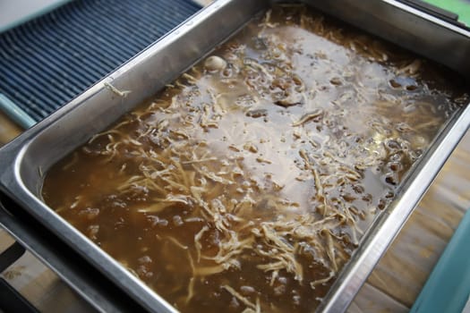 Fish Maw and Chicken Soup in buffet line. The container is a rectangular stainless steel tray. Selective focus.