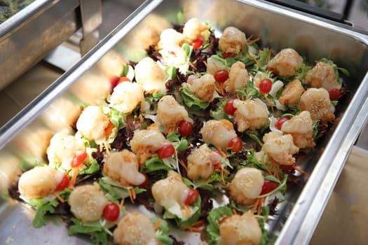 Fried shrimp salad with cream that is arranged in bite size in buffet line. The container is a rectangular stainless steel tray. Selective focus.