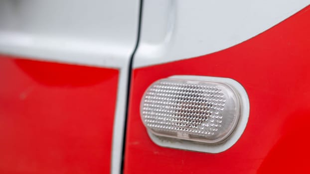 Automotive light bulb. Turn signal on the side of the car. A white turn signal on a red crossover, which is located on the side on the right side of the fender surface