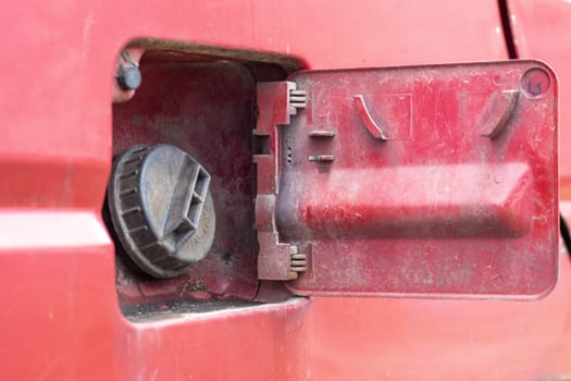 The car's open fuel tank cap was opened to pour gasoline or diesel fuel into the tank at a gas station. The concept of rising fuel prices and transport industry