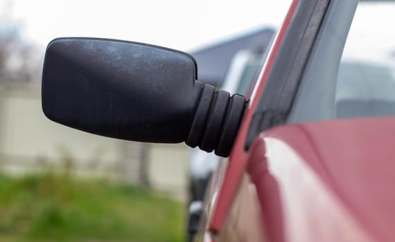 Side left right plastic rearview mirror on a red car. Exterior side view mirror on the passenger side on an old car