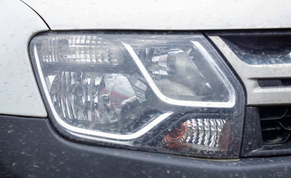 Front right headlight for Renault Duster. Crossover or SUV in white with a black bumper. View of the front of the car. Detailed close-up light on a car. Exterior detail. Ukraine, Kyiv - June 12. 2022