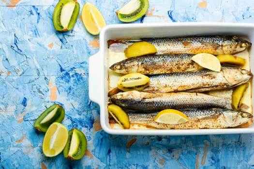 Delicious roasted pelengas in baking dish. Fish with kiwi and lime.