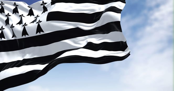 View of the Brittany flag waving in the wind on a clear day. Brittany is a peninsula, historical country, and cultural area in the west of France. Selective focus.