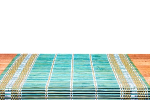 A green yellow bamboo mat on a rustic wooden table isolated on a white background. Template for your product display montage. Space for design.