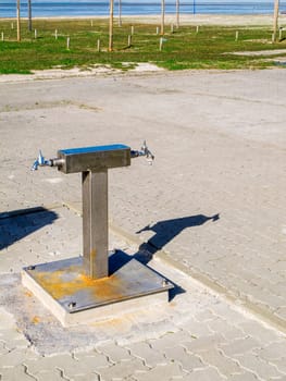 View of a washing area for rubber boots after a mudflat hike with cast shadows on the German North Sea beach in East Frisia near Neuharlingersiel.