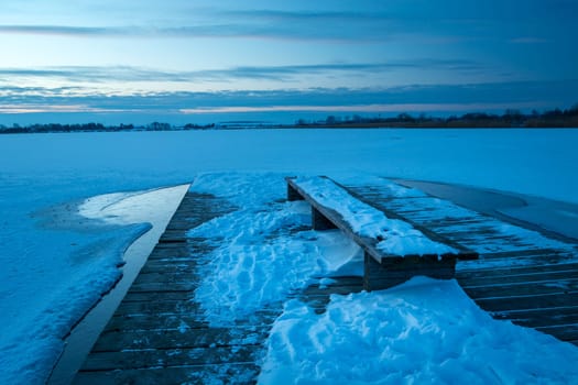 Snow on the pier with a bench and a frozen lake, Zoltance, Lubelskie, Poland