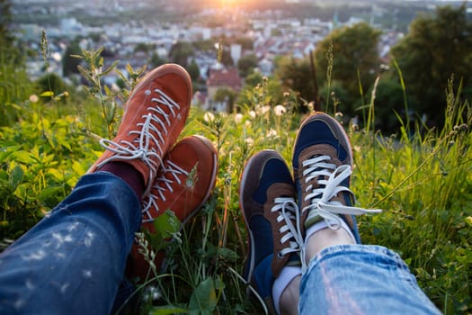 Legs of traveler couple sitting in a park, relaxing and enjoying the view of the city. Freedom concept