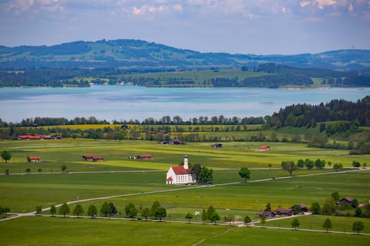 View of the Bavarian 17th century baroque Roman Catholic church St. Coloman and the Forggensee lake in the background, Schwangau, Bavaria