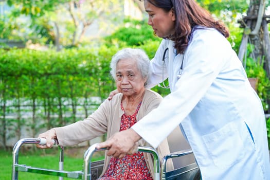 Asian elderly woman disability patient walk with walker in park, medical concept.