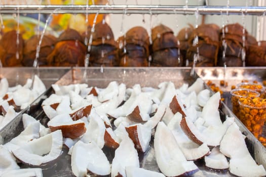 Fresh coconut slices. Water drops falling over pieces displayed at street market stall