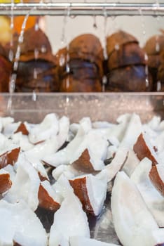 Fresh coconut slices. Water drops falling over pieces displayed at street market stall