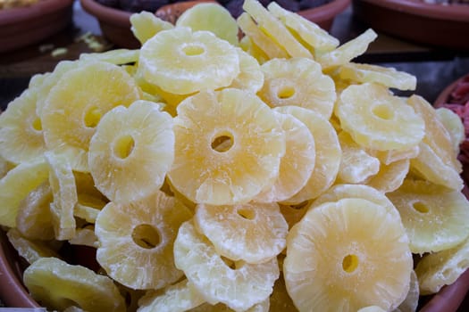 Bowl with pineapple dried fruit. Slices displayed at street market stall