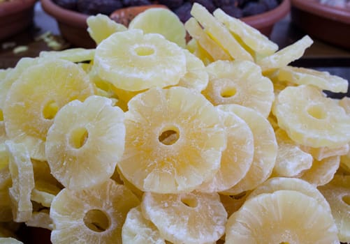 Bowl with pineapple dried fruit. Slices displayed at street market stall