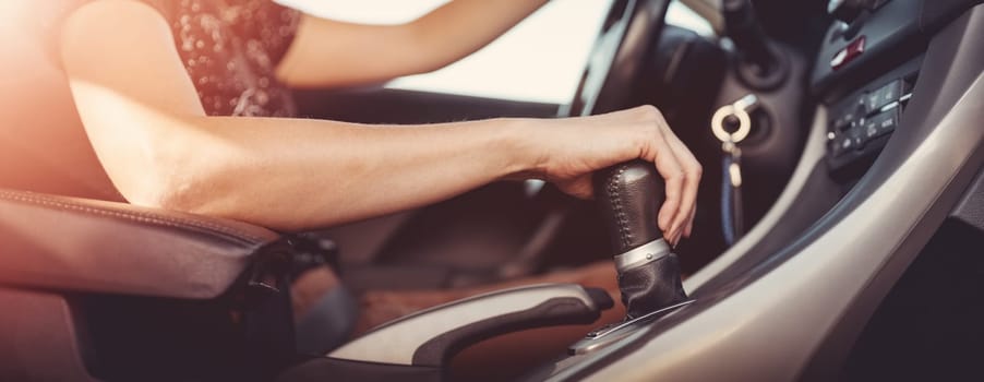 Woman driving a car and shifting gears on the gearbox. Concept of vacation and travel.