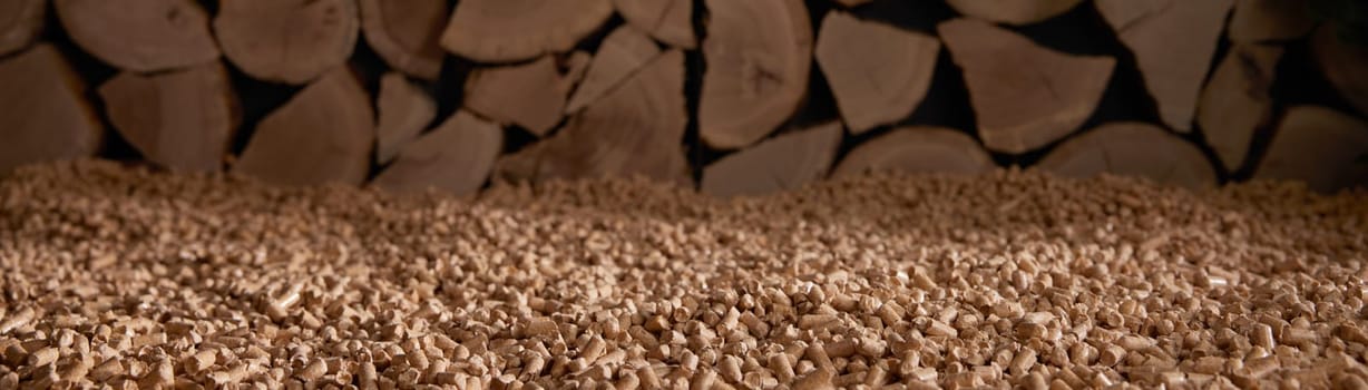 Stack of solid wood fuel pellets scattered on ground near chopped firewood in sunlight