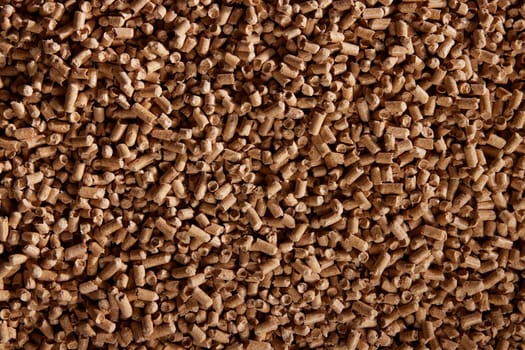 Top view of natural background of heap of cylindrical wood pellets scattered on surface in daytime