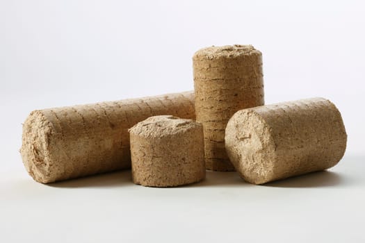 Cylinder shaped compressed solid biomass briquettes placed on white table in light studio
