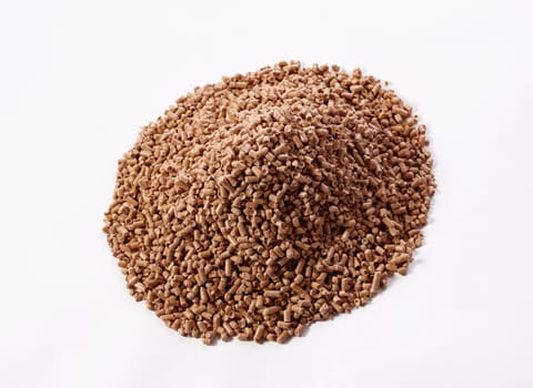 From above of pile of natural wood fuel pellets arranged on white background in studio