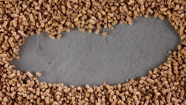 From above of natural background created with pile of beige wood fuel pellets scattered on gray concrete table