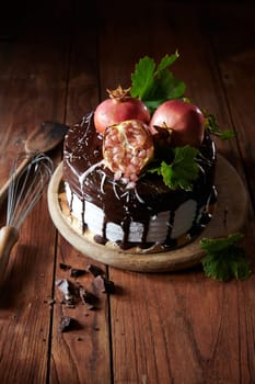 From above of delicious decorated cake made of figs and pomegranate with chocolate smudges served on wooden table with utensils