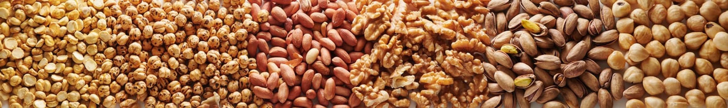 Wide angle view heap of various types of tasty pistachio and hazelnut nuts with walnuts and peanuts arranged together in rows