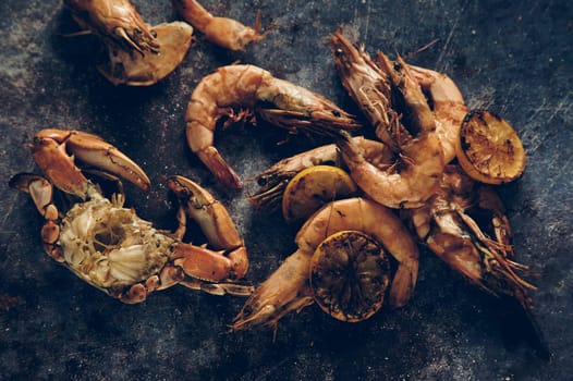 Top view of raw shrimps and crabs with claws placed together on gray background in light kitchen during cooking preparation