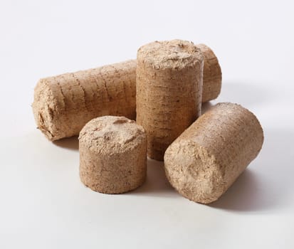 From above of cylinder shaped biofuel briquettes of various sizes placed on white background