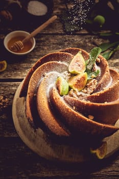From above of sweet powdered sugar sprinkling on tasty freshly baked fig cake with decoration served on cutting board in kitchen