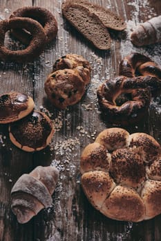 From above different types of baked sweet confectionery placed on messy wooden table with fresh Turkish bread in light bakery