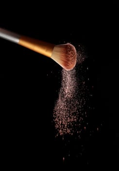 Make up brush with cosmetic powder splash, over black background. Splash image