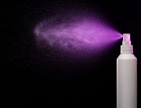 Spraying product in spray bottle over black background