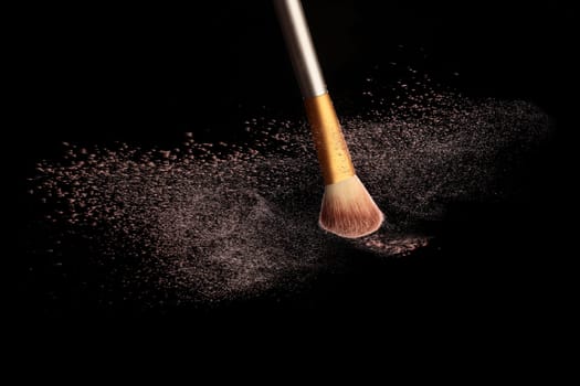 Make up brush with cosmetic powder splash, over black background. Splash image