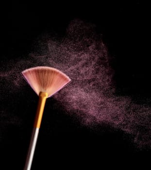 Make up brush with cosmetic powder splash, over black background. Splash image