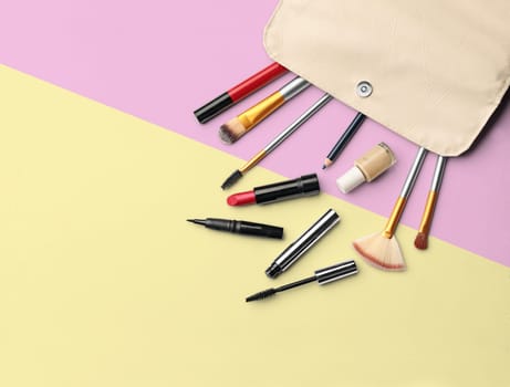 Make up products. Lipstick, powder, shadows with cosmetic bag. Image with copy space. Colored background