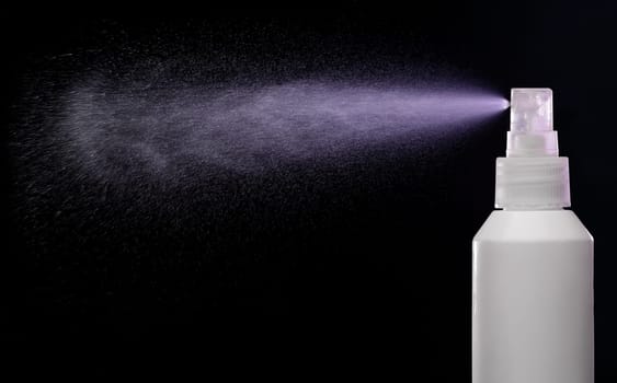 Spraying product in spray bottle over black background